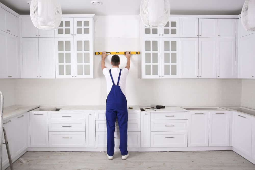 Contractor measuring a kitchen space for accurate cabinet installation.
