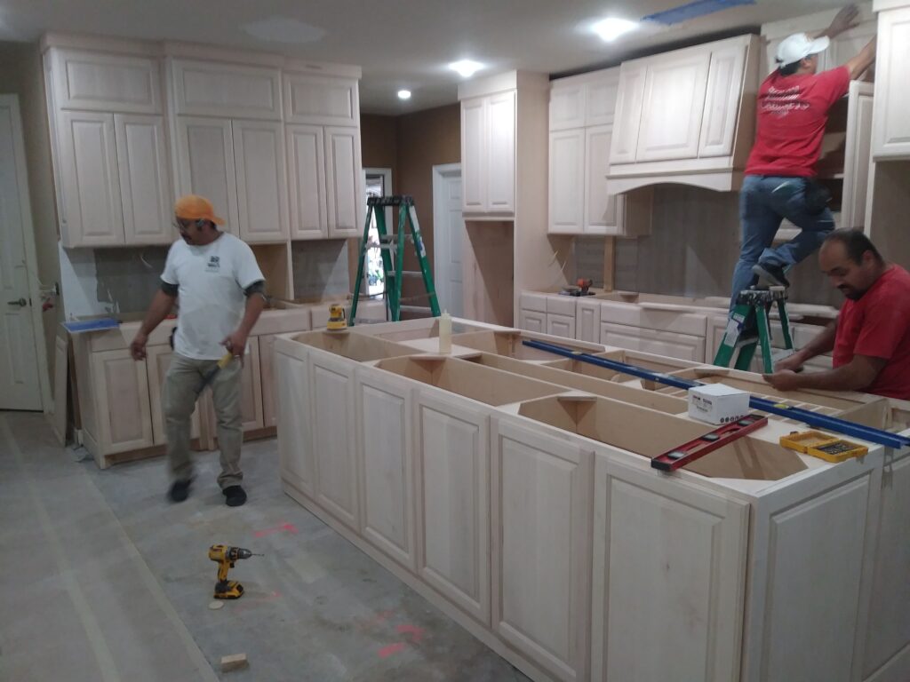 Contractors installing home kitchen cabinets in a factory-built shell